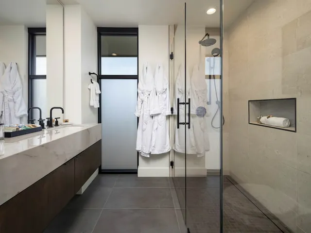 Bathroom with a stone vanity, robes and a glass shower