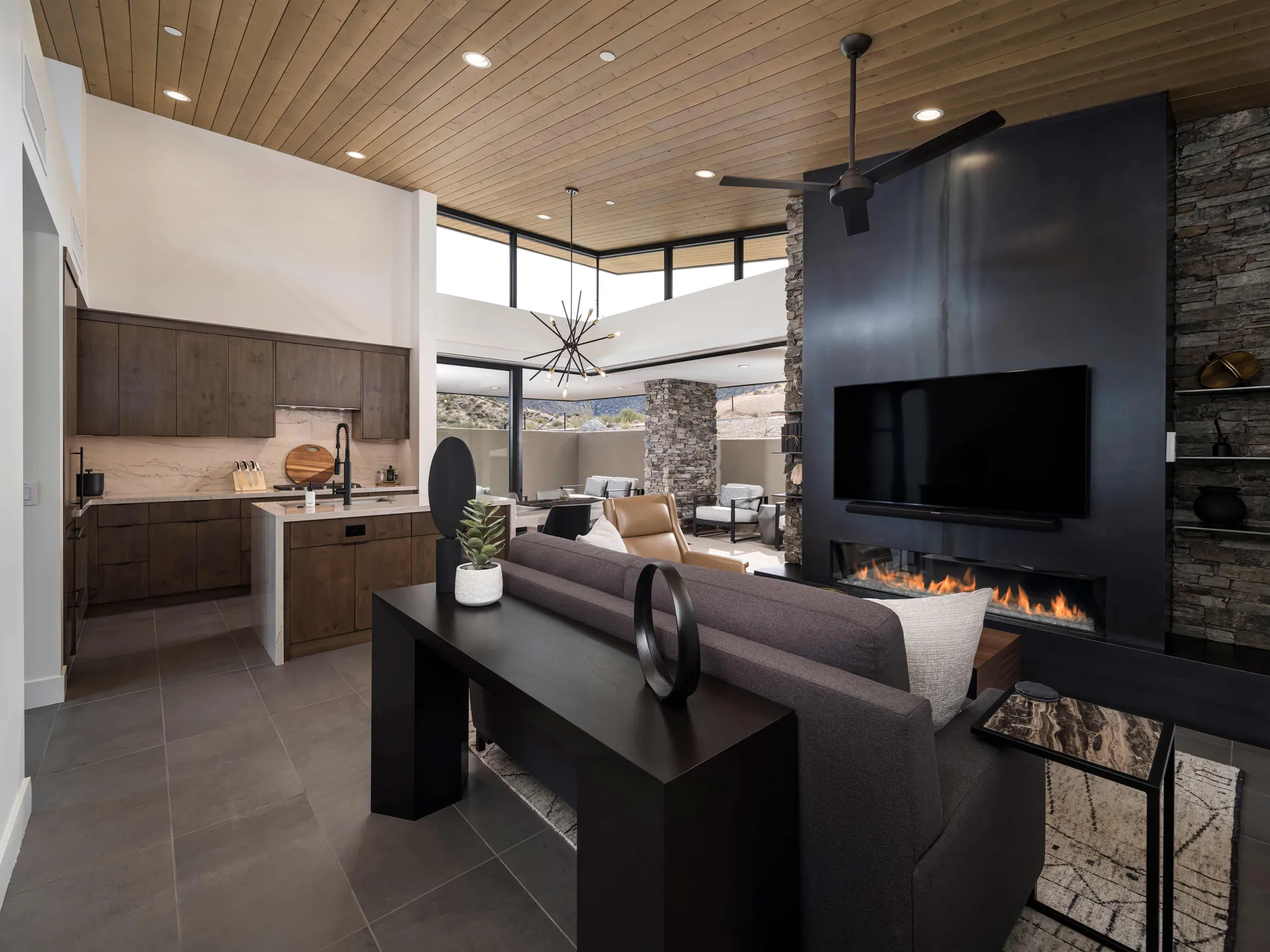 Basalt's great room: a steel fireplace wall, a long sofa and the kitchen beyond