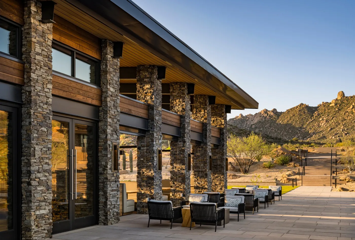 The Lodge's stone terrace with lounge chairs and the mountains behind