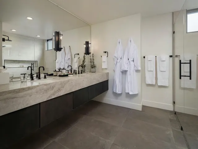 Main bathroom with a stone vanity, robes and a glass shower